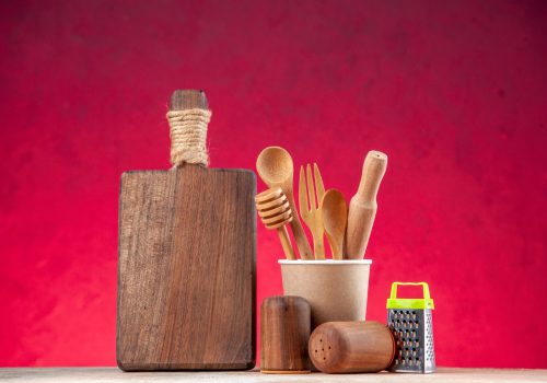 top-view-wooden-spoon-empty-plastic-coffee-pot-cutting-board-grater-pink-surface